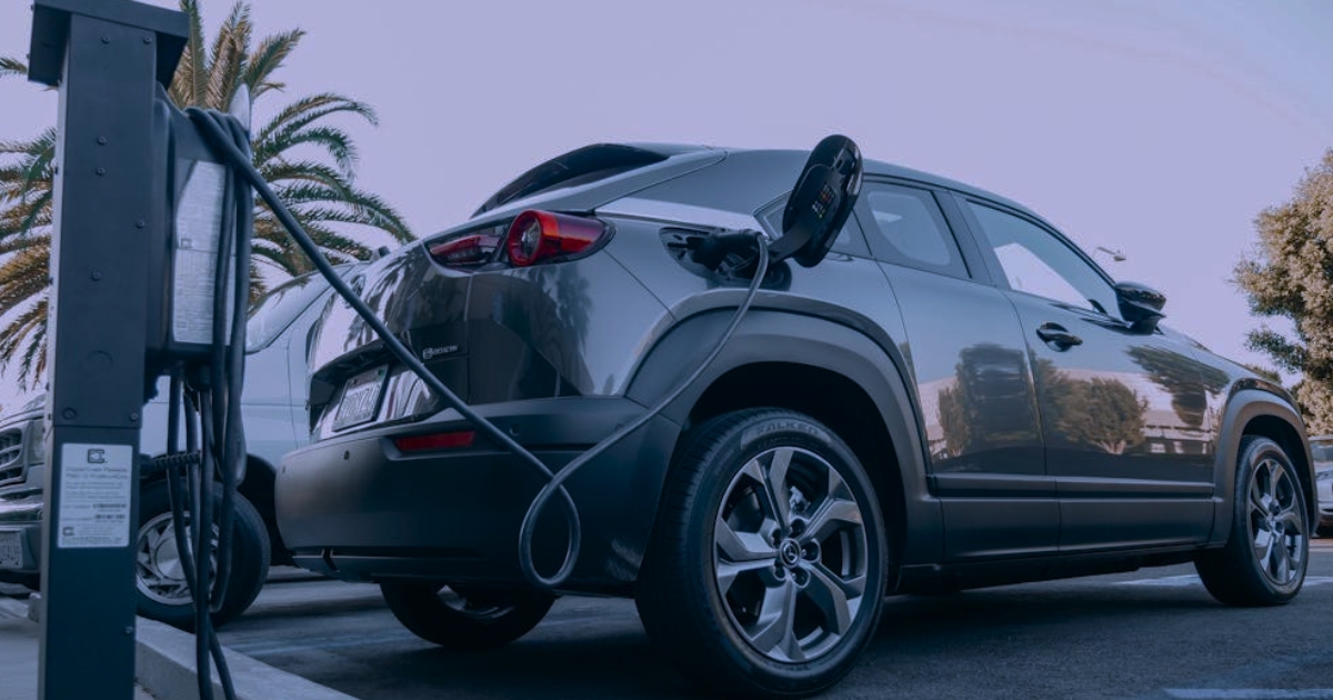 A close-up shot of a black electric vehicle charging cable plugged into the open charge port
